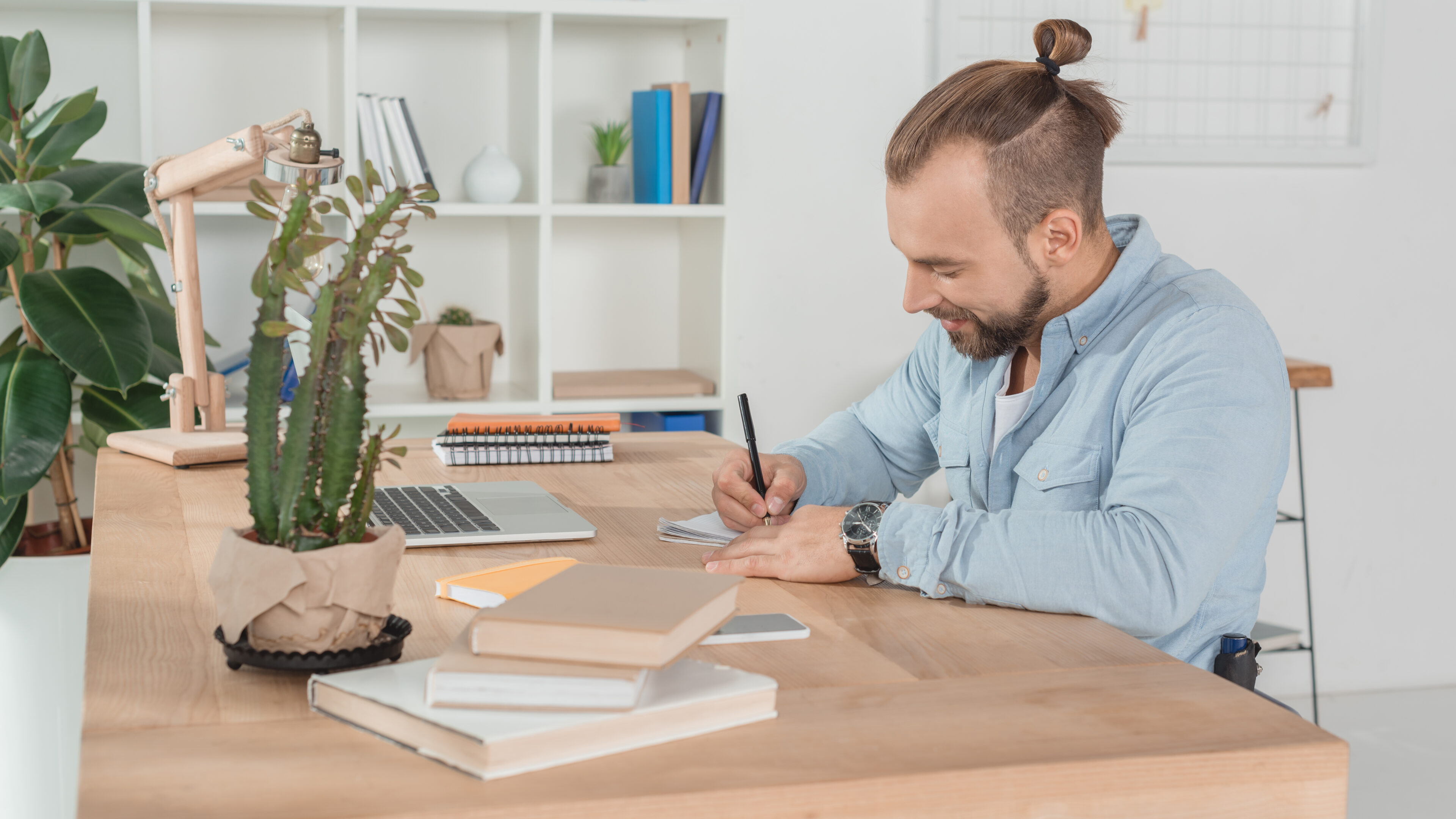 happy disabled man on wheelchair writing in notebook at workplace